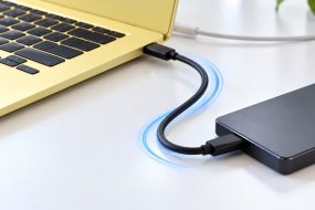 Yellow laptop connected to an external SSD with a USB-C cable.